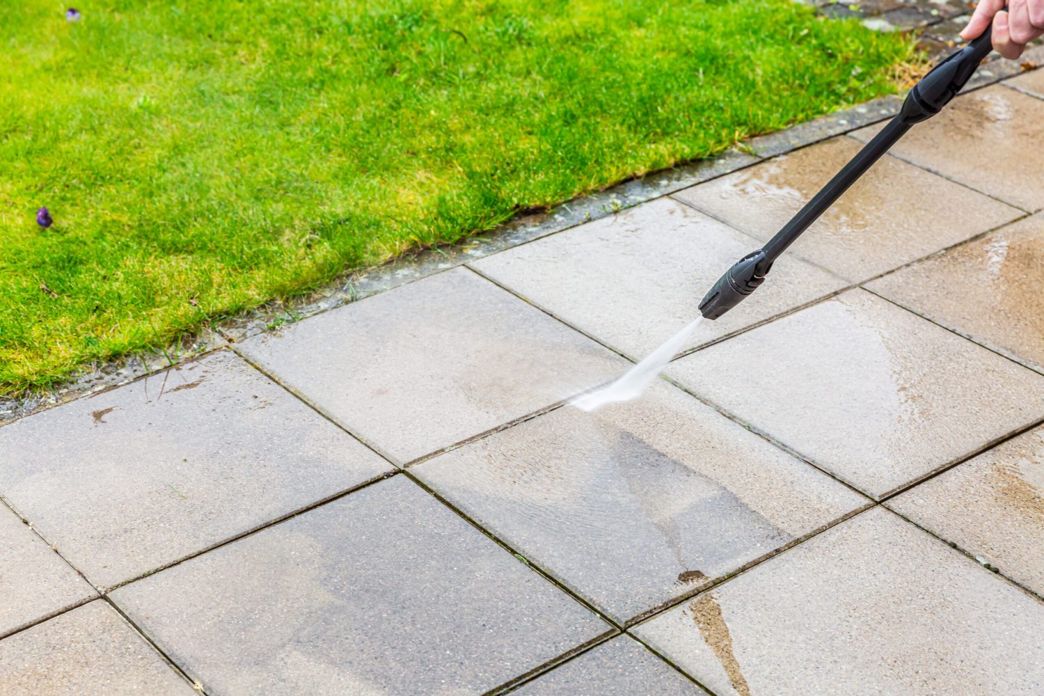 Detail of cleaning terrace with high-pressure water blaster, cleaning dirty paving stones